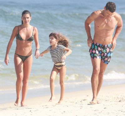 Cau� Reymond pega praia com filha e namorada e esbanja bom humor com bermuda de estampa de picol�s